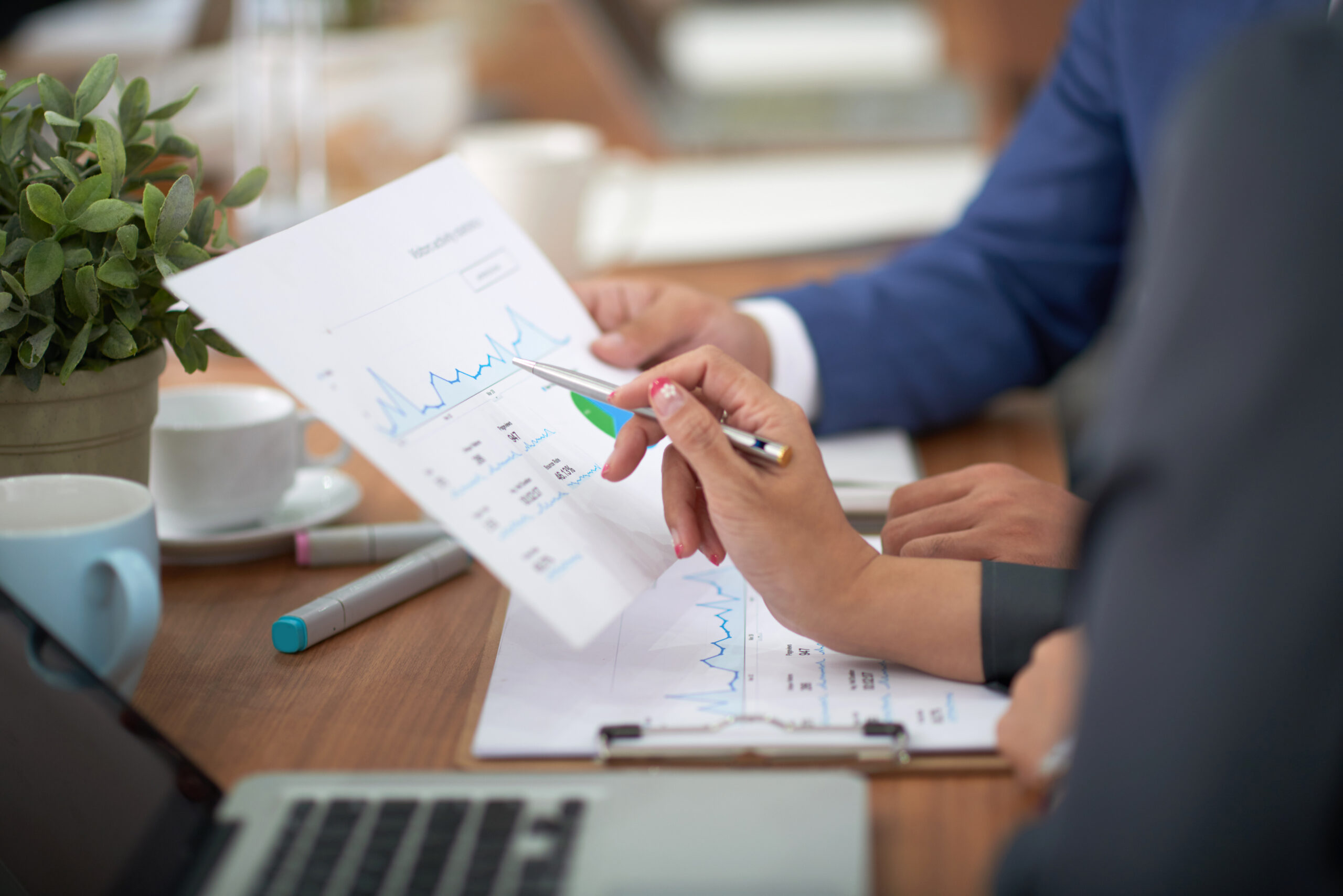 hands man woman business attire sitting desk office discussing graph